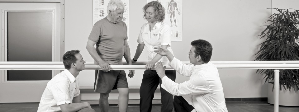 Rehabilitations-Maßnahme nach der Amputation eines Beines. 
Ein Patient und medizinisches Personal interagieren in einer Rehabilitationseinrichtung.